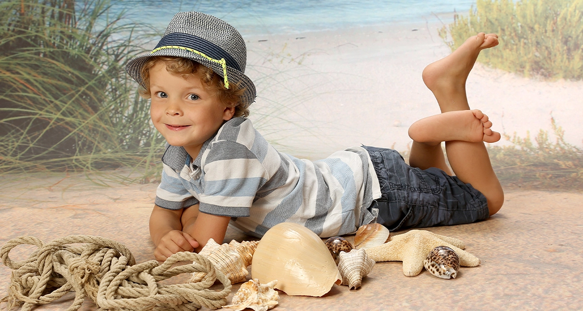 Kindergarten Bild Kind liegend am Strand