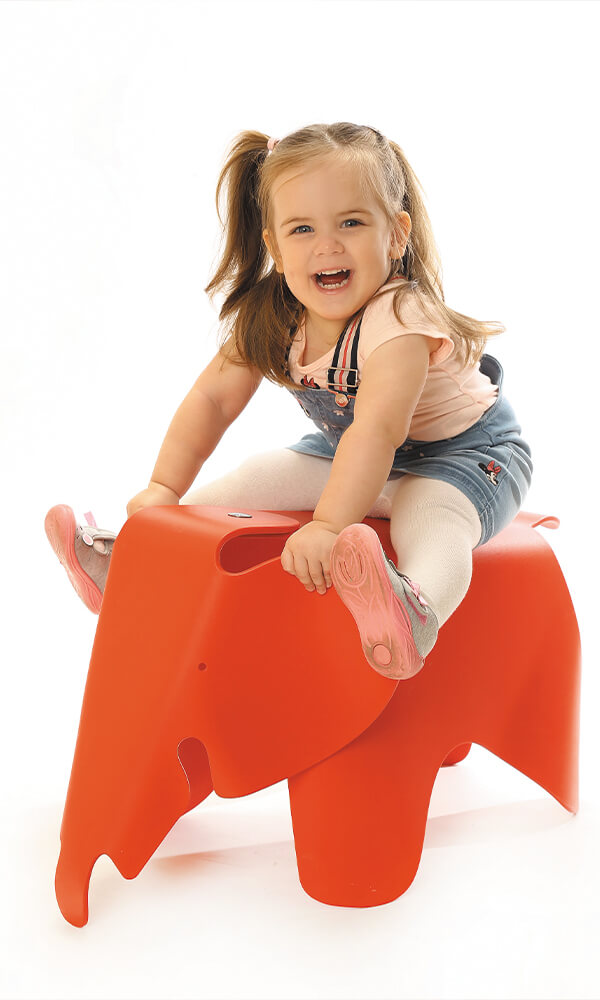 Kindergarten Bild Kind sitzend auf Elefant Spielzeug rot