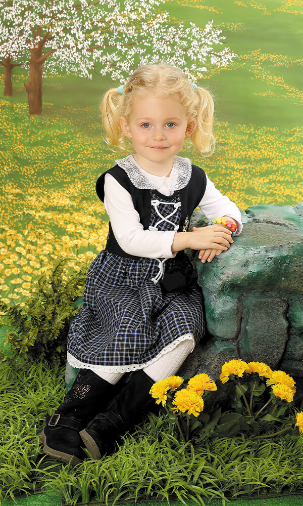 Kindergarten Bild Kind Blumen Natur am Stein sitzend